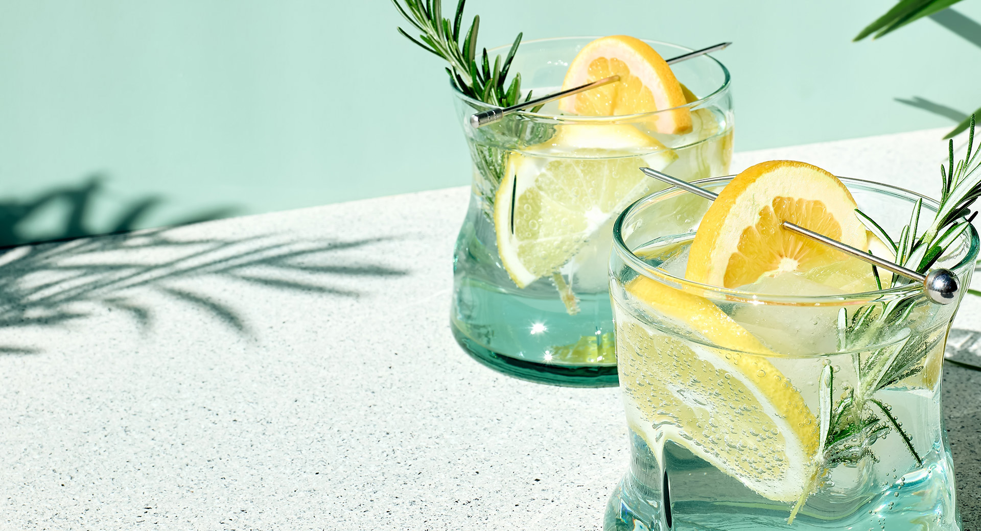 Two glasses with lemon slices and rosemary sprigs