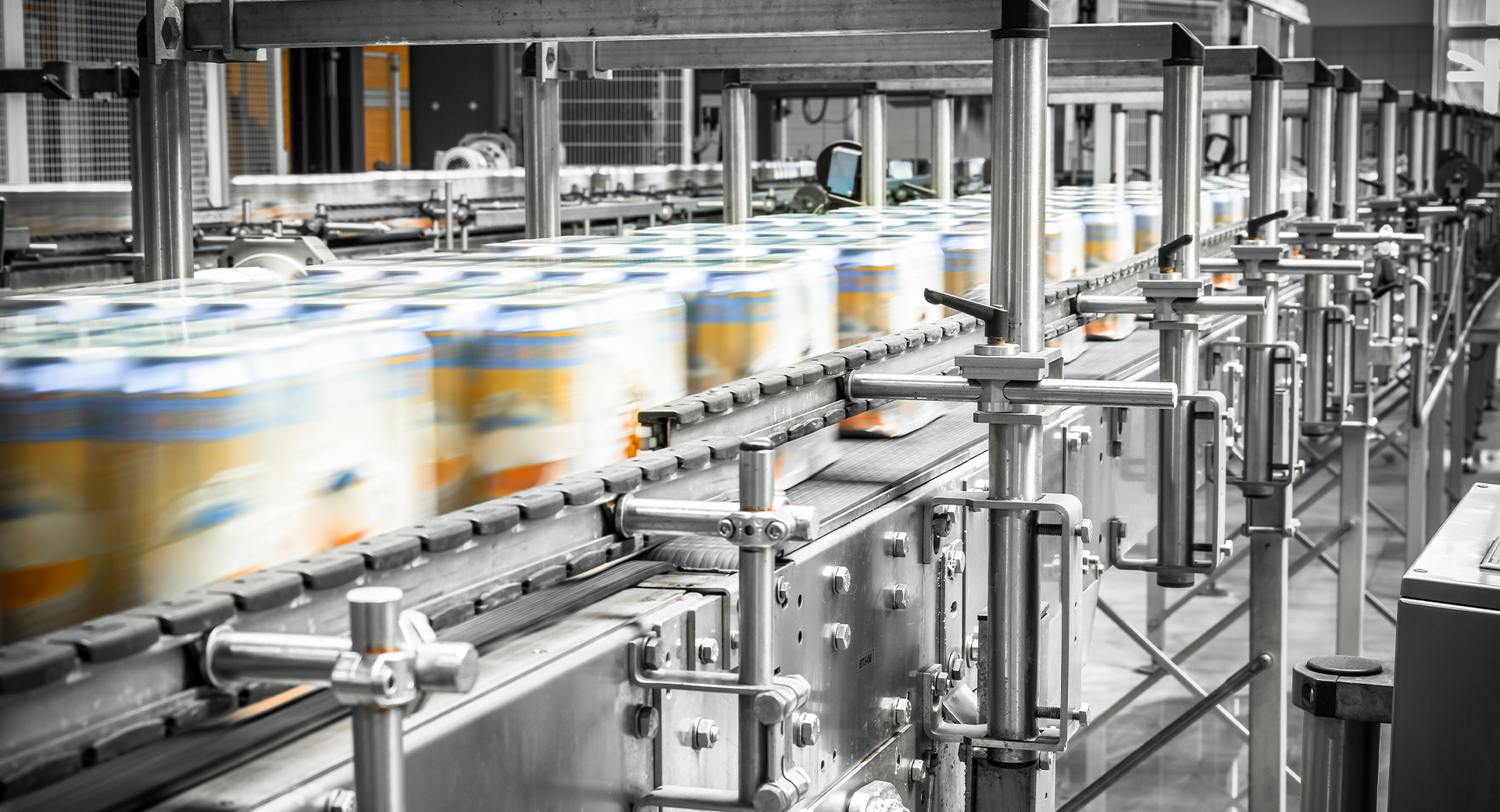 Cans going through the assembly line in batches.  All the cans have labels, indicating they are moving fast.