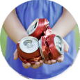 Child holding three crushed cans to recycle